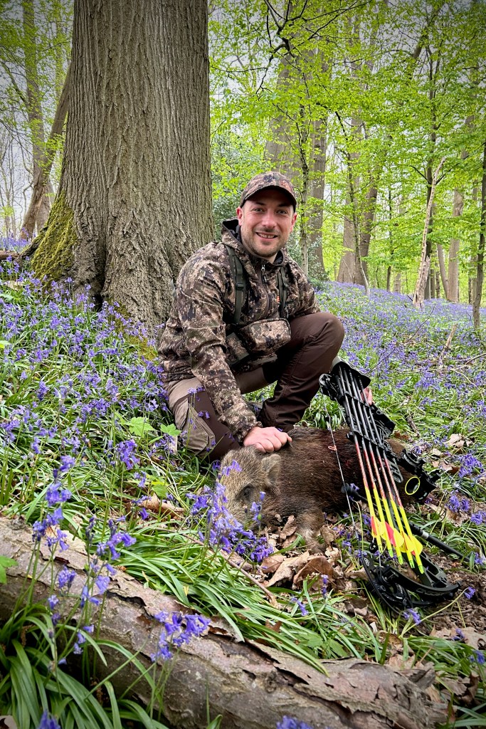 Chasseur à l'arc avec une bête rousse dans un sous-bois de jacinthes sauvages au printemps