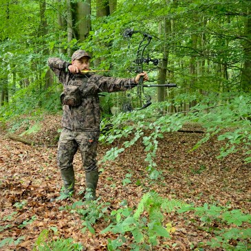 Chasseur à l'arc en position de tir avec une tenue multicouches offrant une grande liberté de mouvement