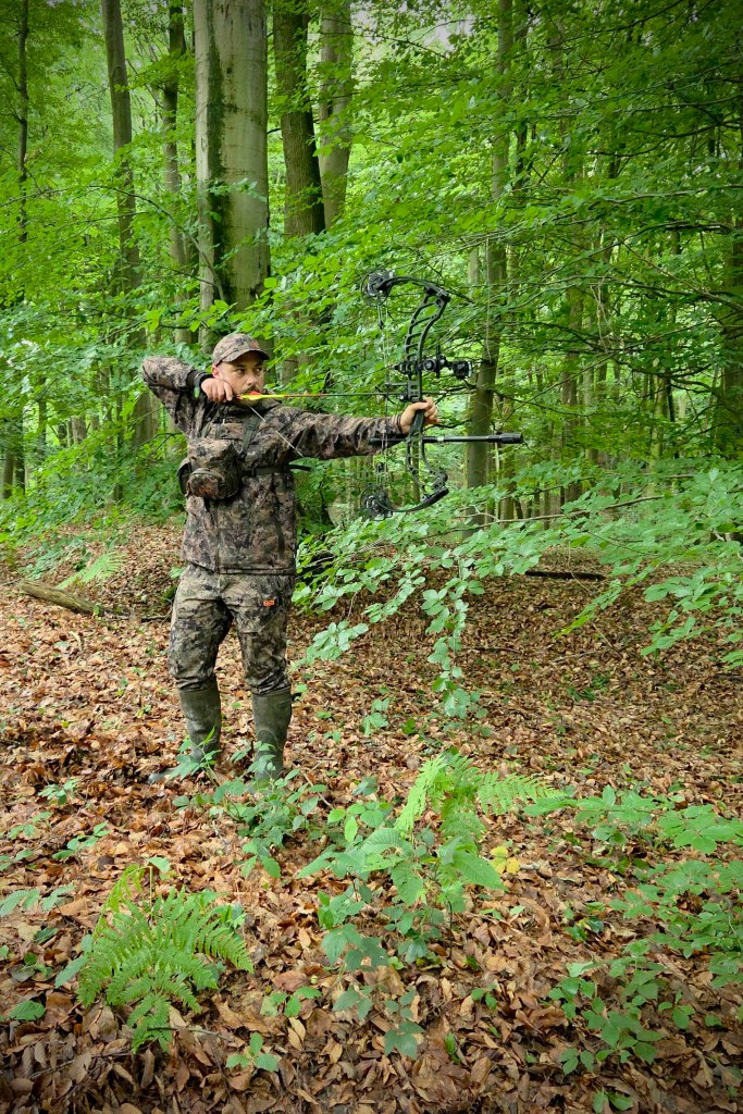 Chasseur à l'arc en position de tir avec une tenue multicouches offrant une grande liberté de mouvement
