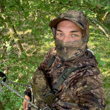 Chasseur installé dans une plateforme de chasse en hauteur lors d'un affût en forêt.