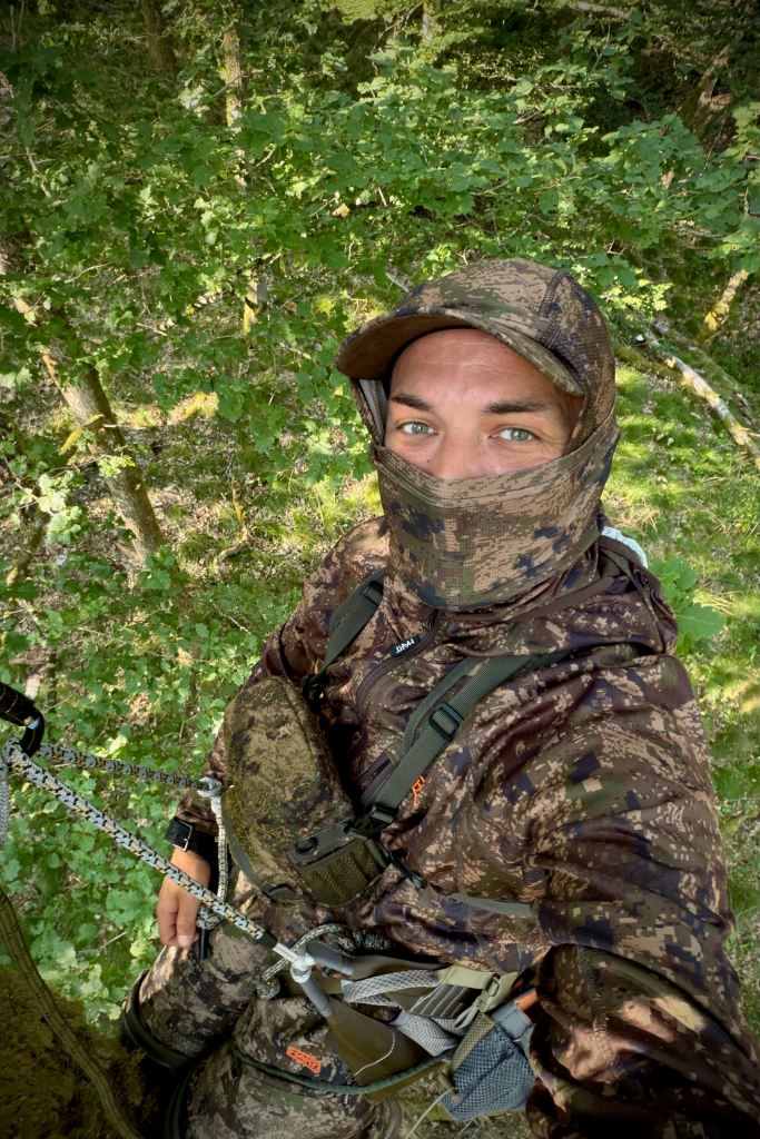 Chasseur installé dans une plateforme de chasse en hauteur lors d'un affût en forêt.