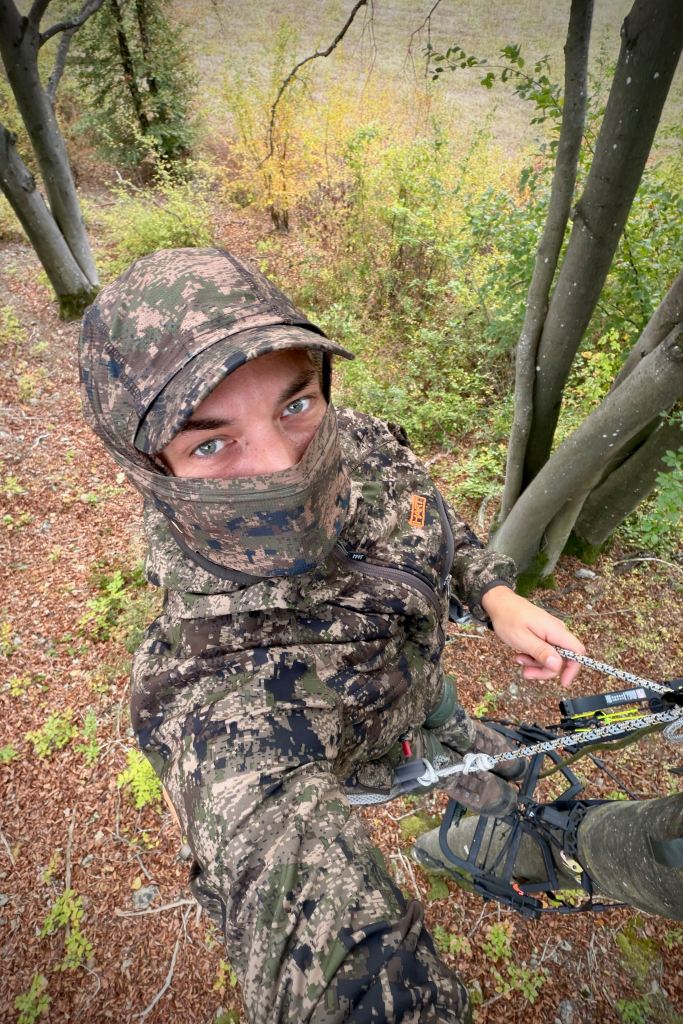 Chasseur à l'arc en tenue camouflée installé en hauteur dans un bois à Lompret